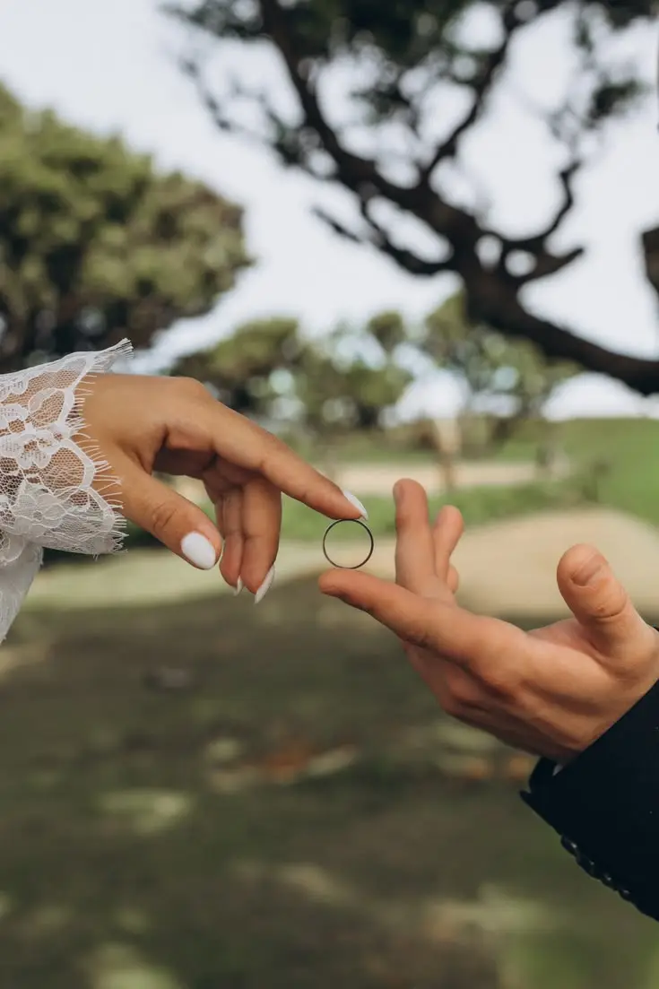 Two hands exchanging a ring outdoors